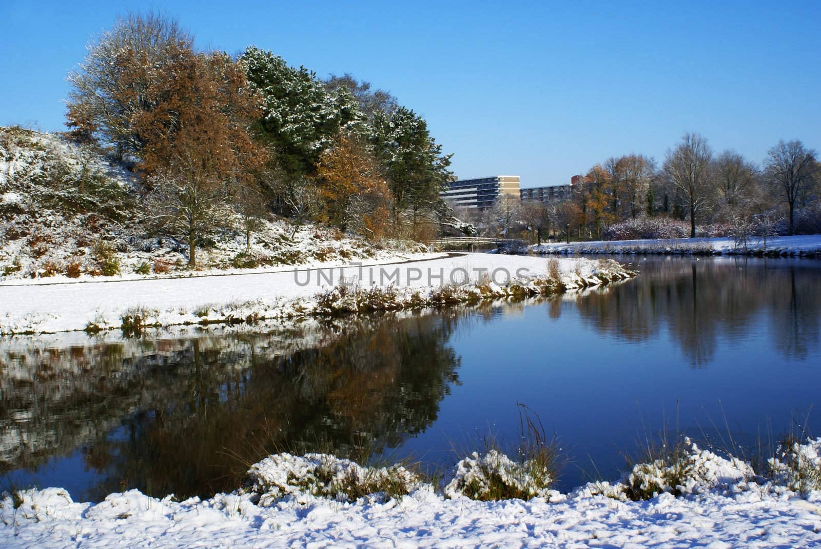 A pond with wonderful reflection in snowy nature with a blue sky.