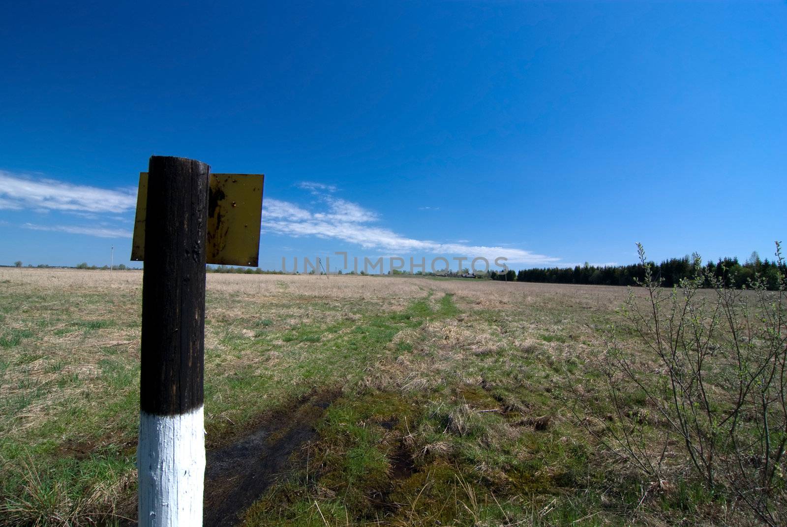 Black-and-white column in the field, against the blue sky