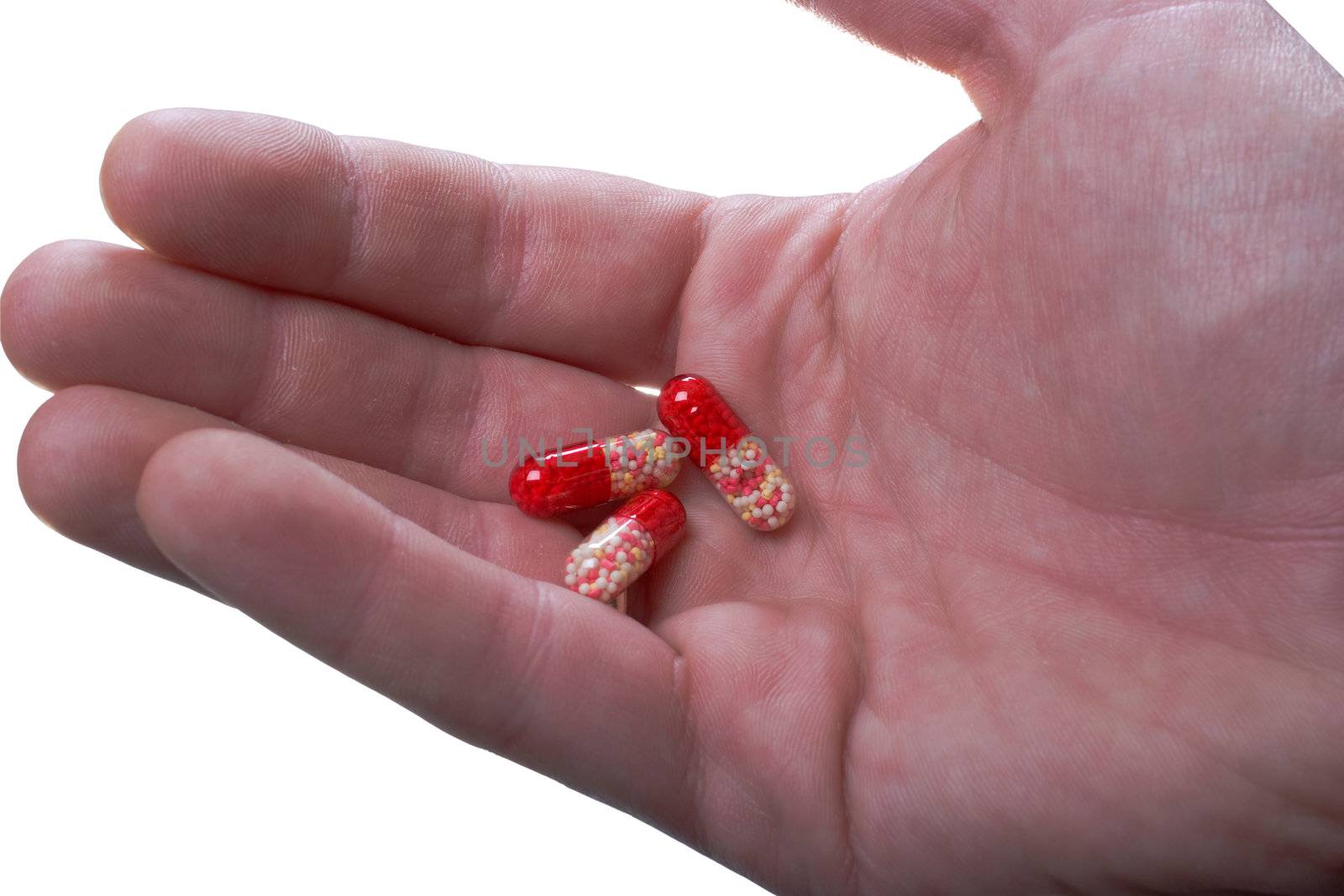 Multi-coloured capsules on a palm. It is isolated, on a white background