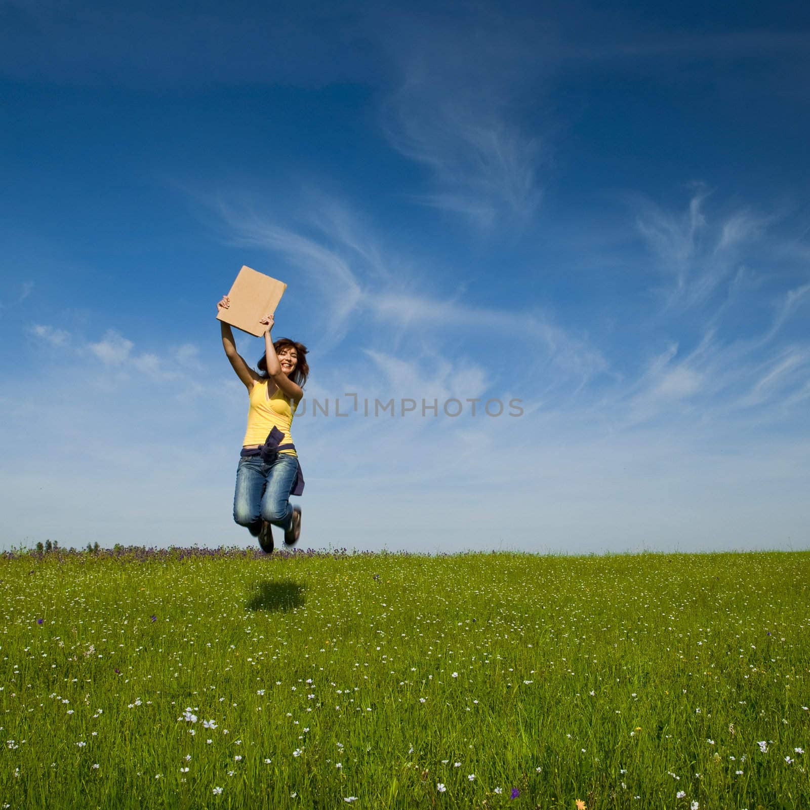 Beautiful young woman jumping and holding a blank paper card