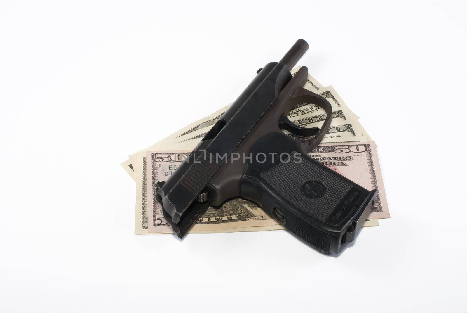 The pistol lays on dollar banknotes on a white background