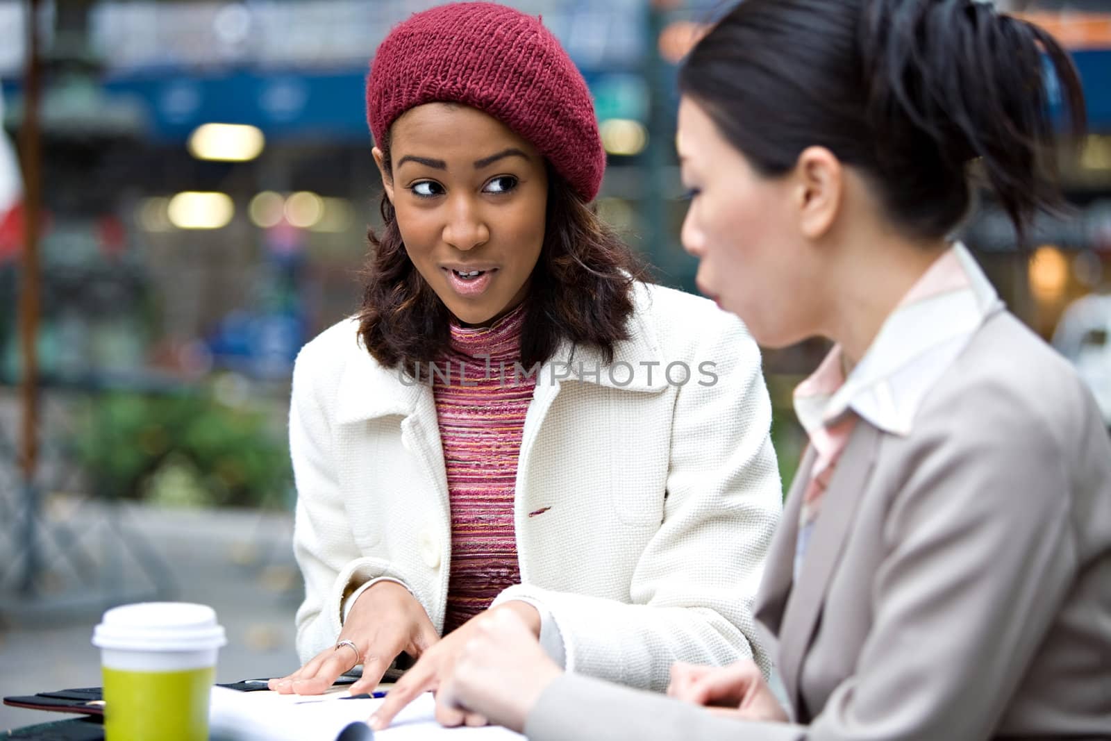 Two business women having a casual meeting or discussion in the city. Shallow depth of field.