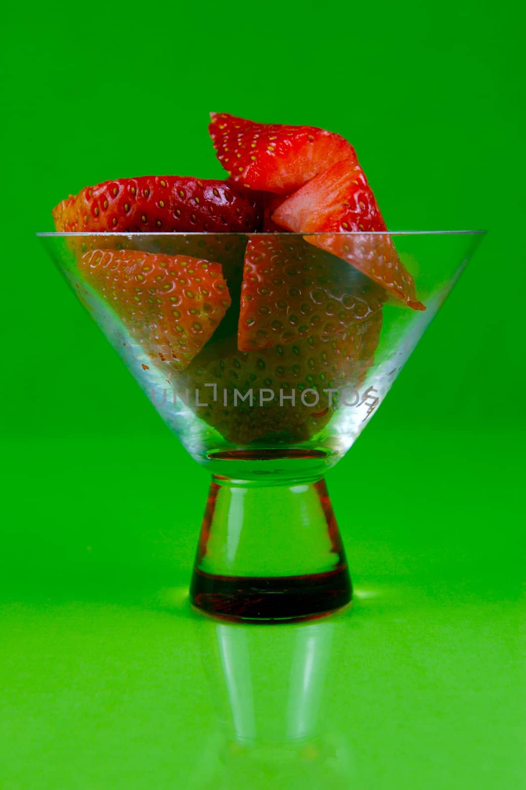 Strawberries in a cocktail glass islolated against a green background