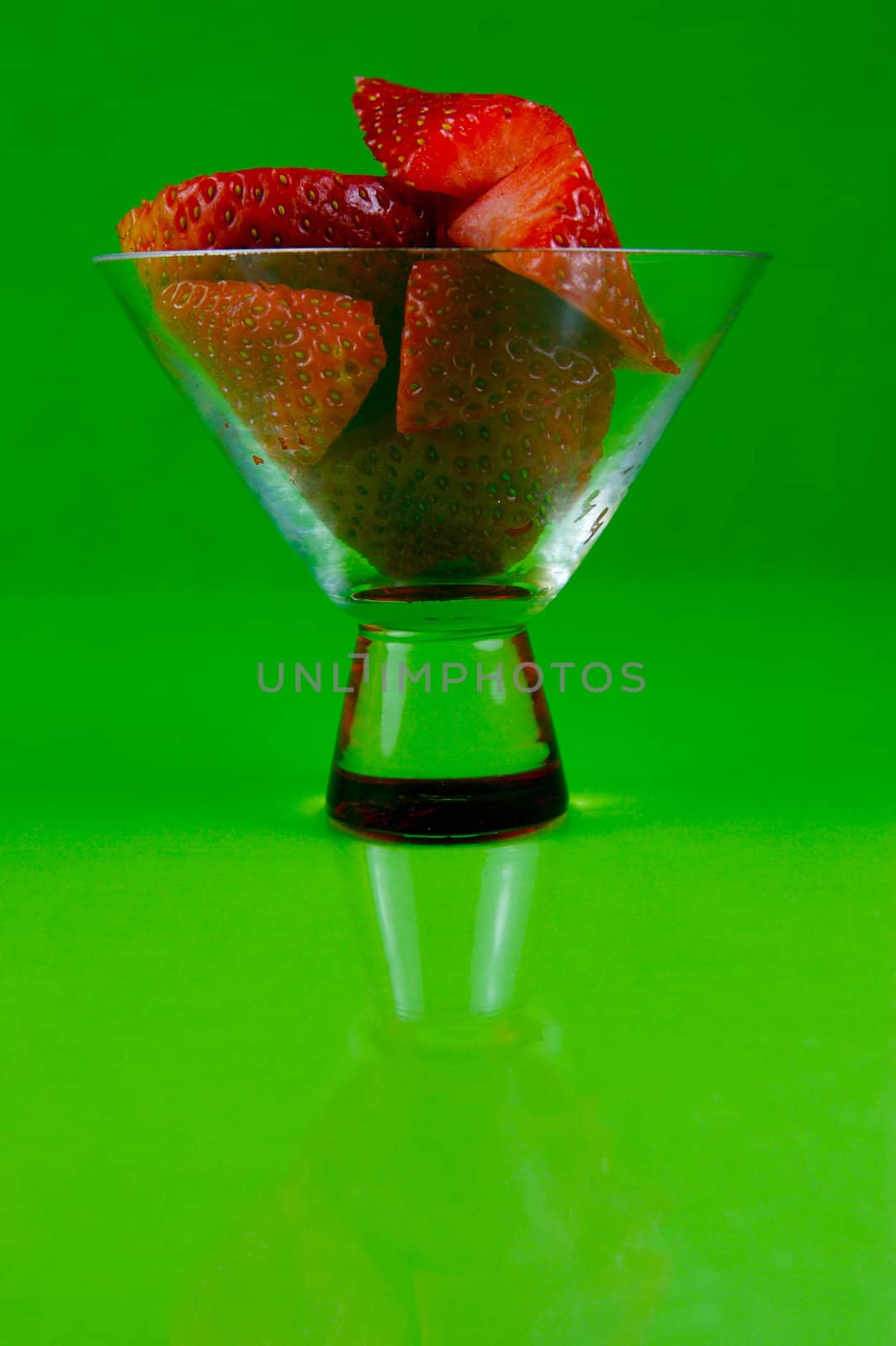 Strawberries in a cocktail glass islolated against a green background