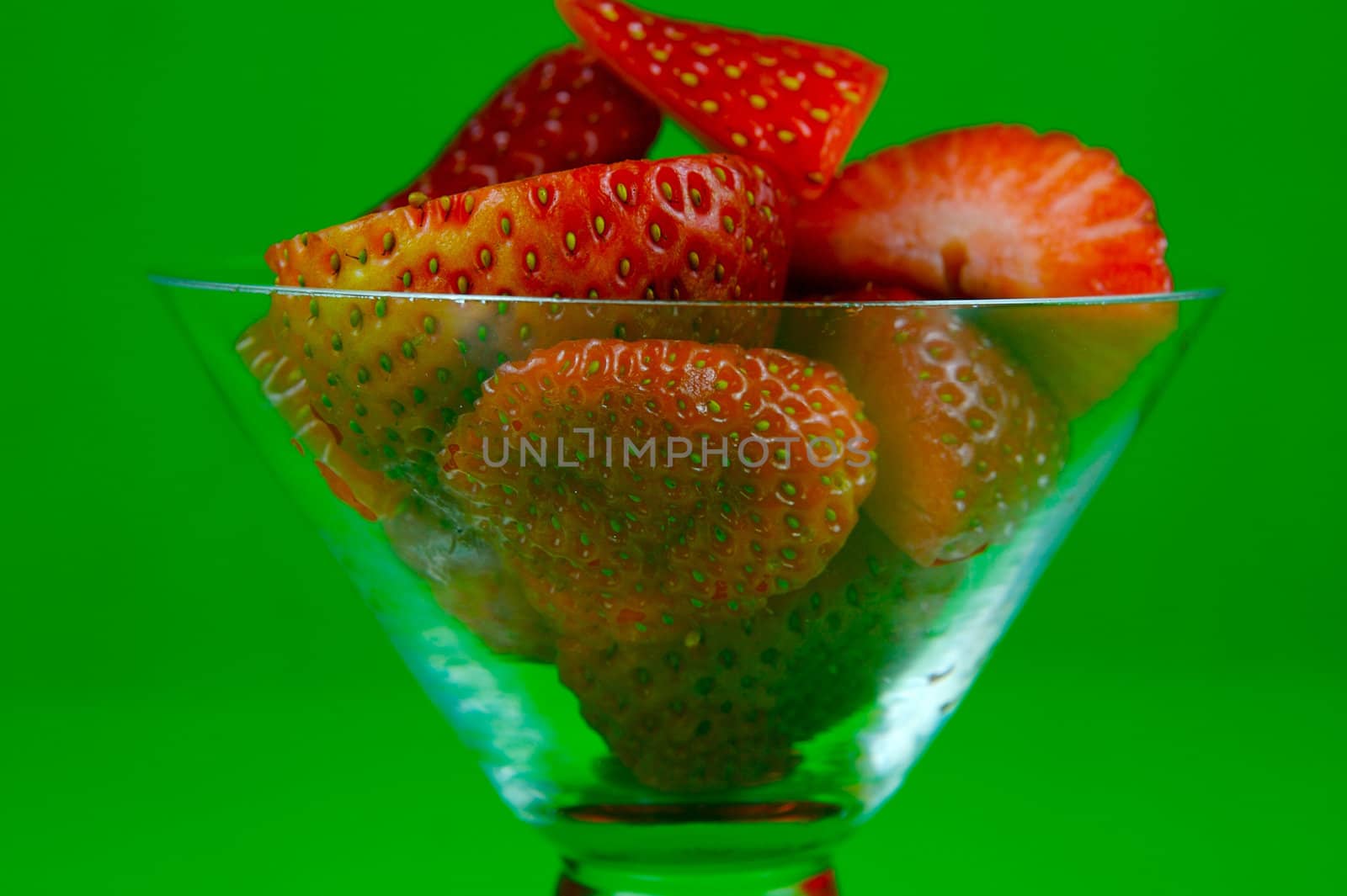 Strawberries in a cocktail glass islolated against a green background