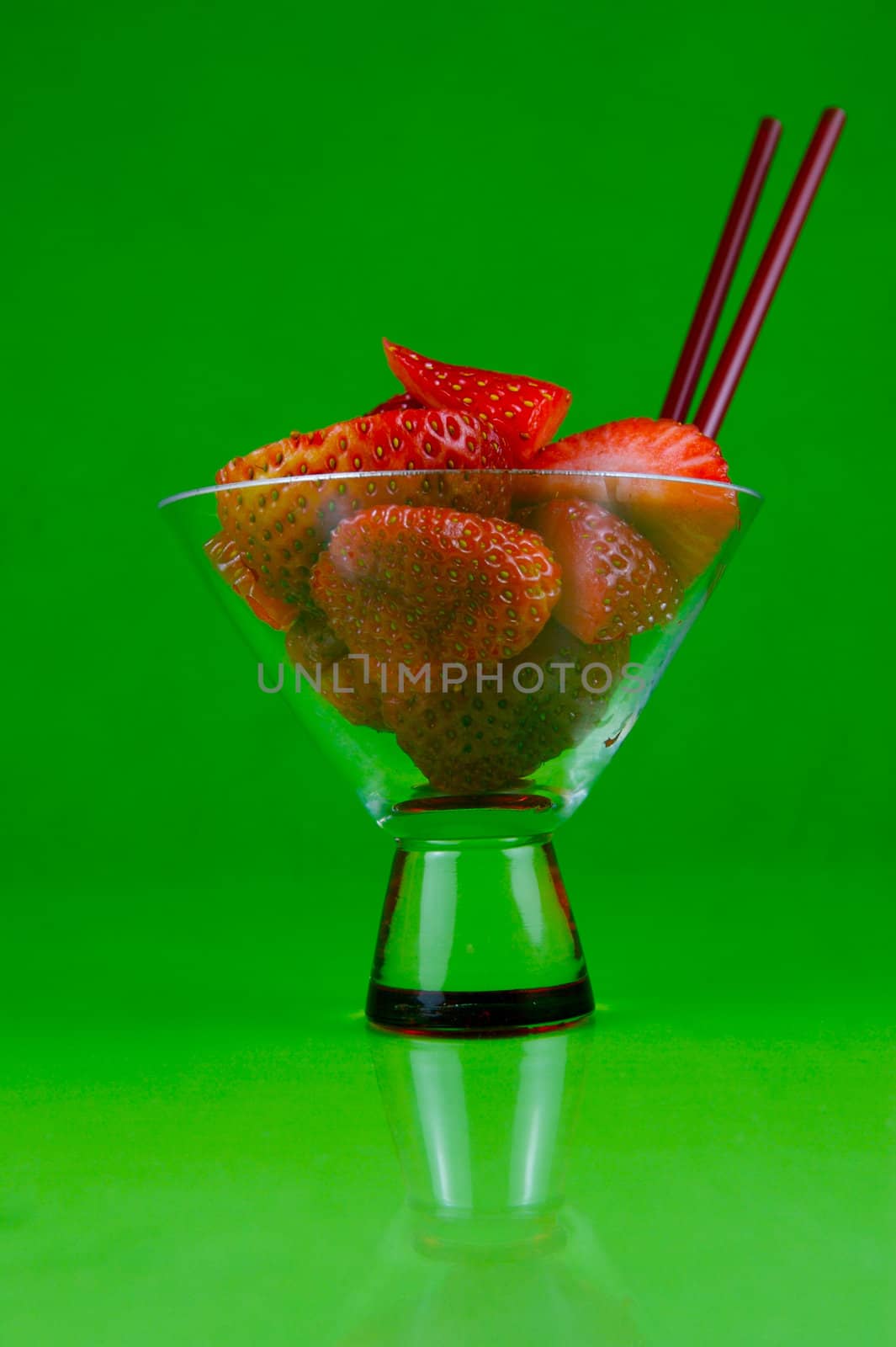 Strawberries in a cocktail glass islolated against a green background