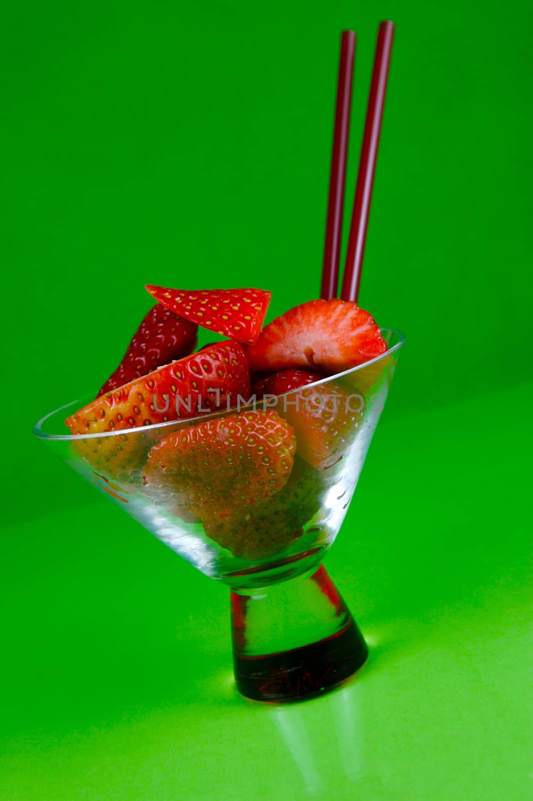 Strawberries in a cocktail glass islolated against a green background