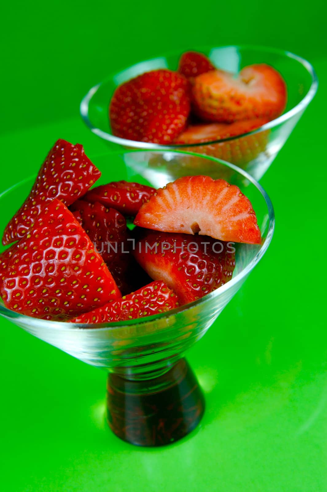 Strawberries in a cocktail glass islolated against a green background