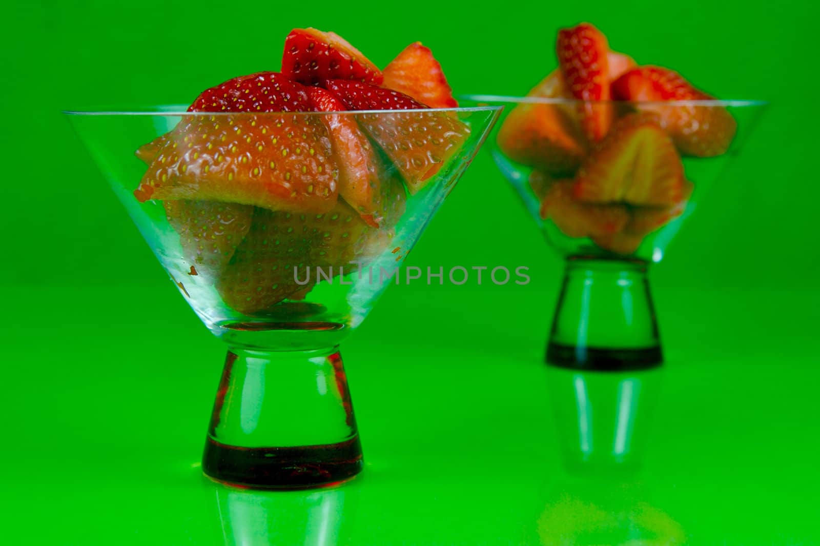 Strawberries in a cocktail glass islolated against a green background