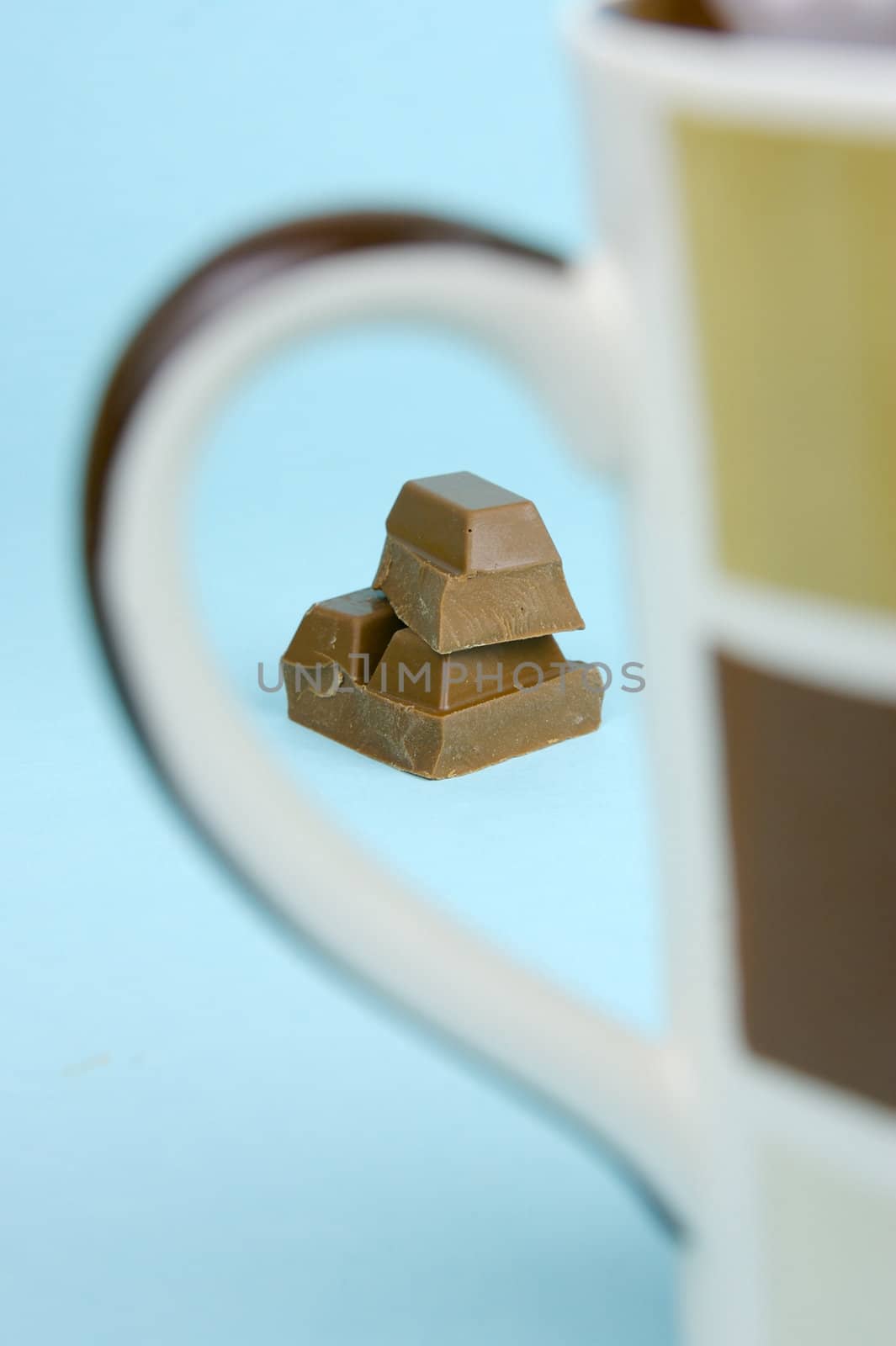 Milk chocolate isolated against a blue background with coffee mugs
