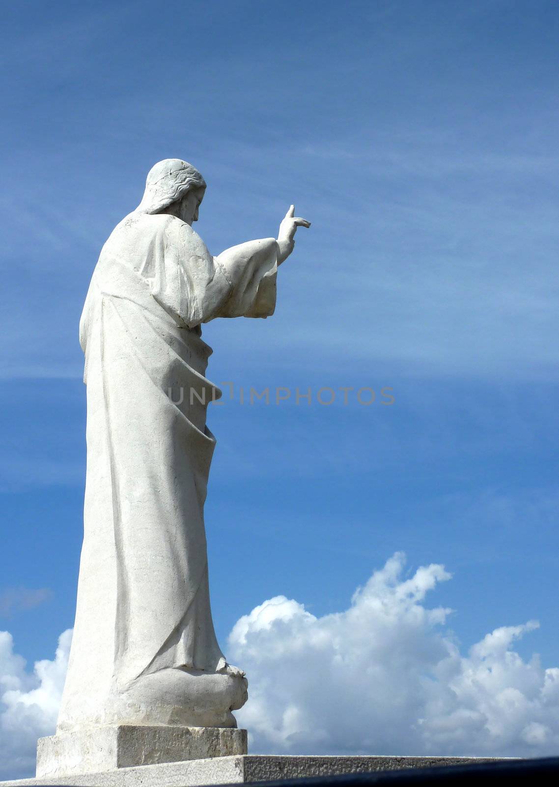 Statue of Jesus holding his hand and made of white stone and viewed from the right side, at Marseilles, France, by beautiful weather