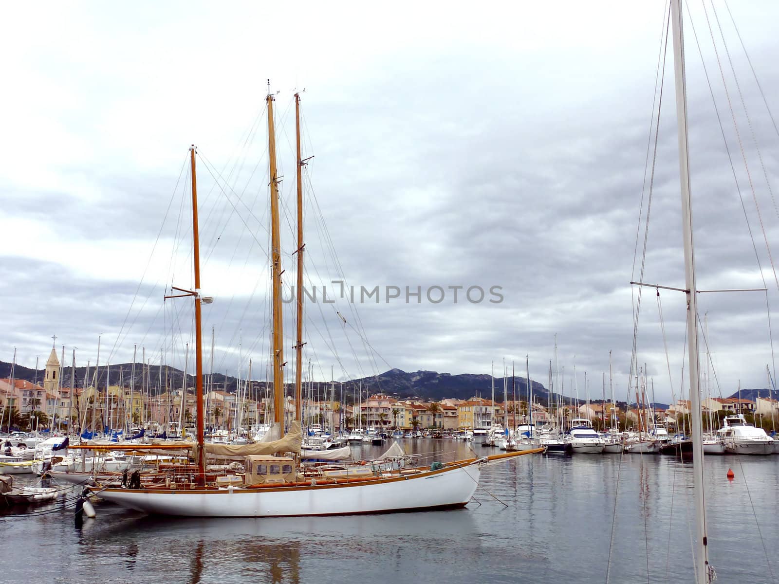 View of Sanary-sur-mer harbor with a beautiful white wood boat, by cloudy weather, France