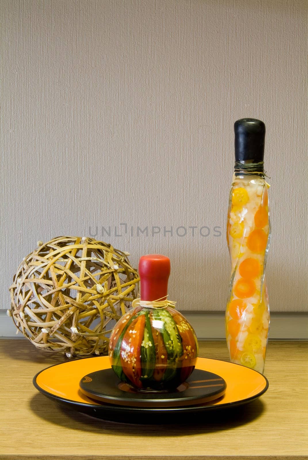Decorative bottles, straw sphere and the ceramic plate on the table