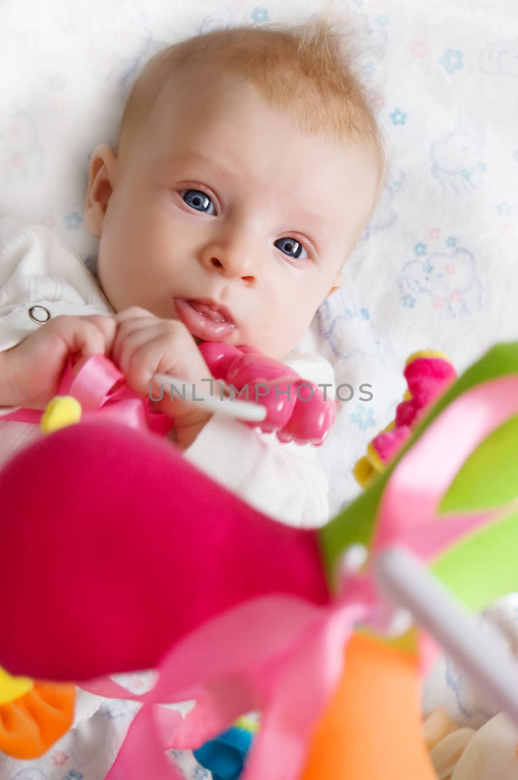 Three months old baby girl playing with toys