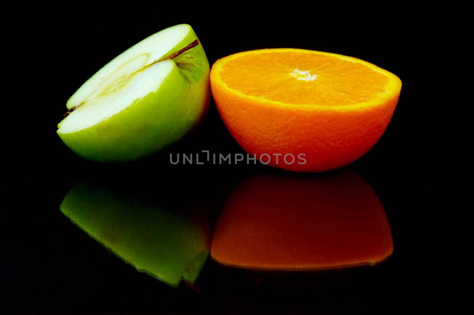 Apple and oranges isolated against a black background