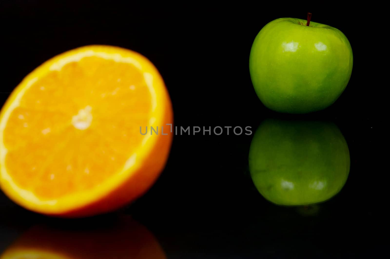 Apple and orange halves isolated against a black background