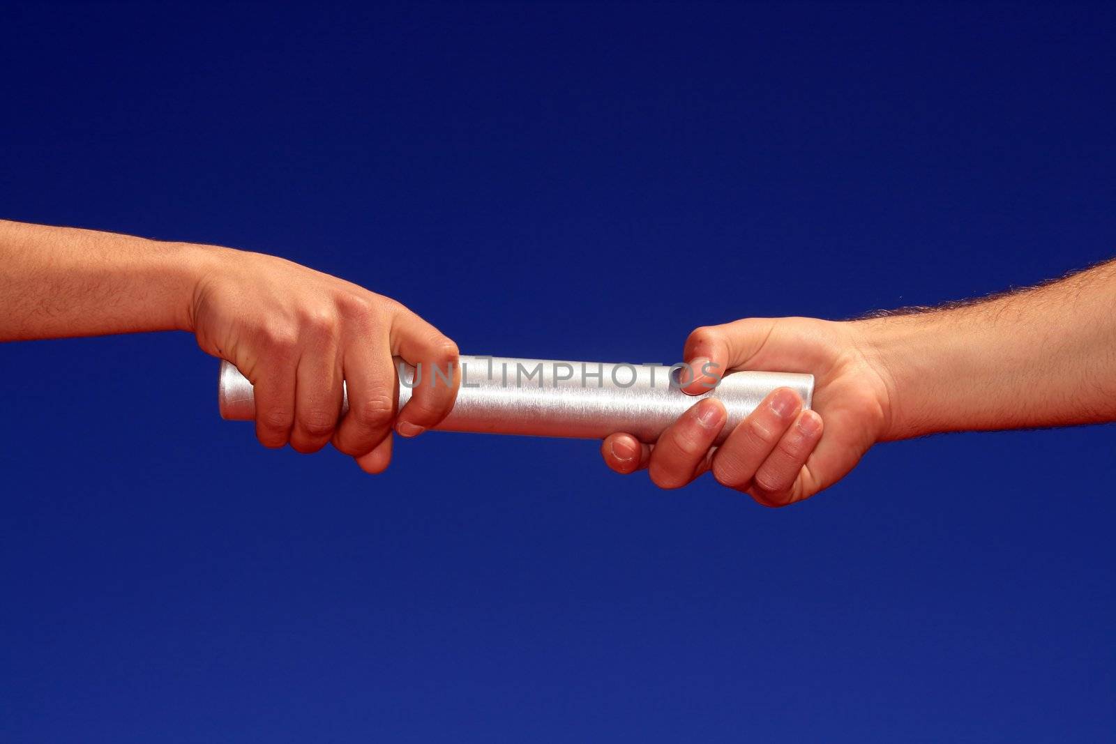 hands passing the batton against blue sky