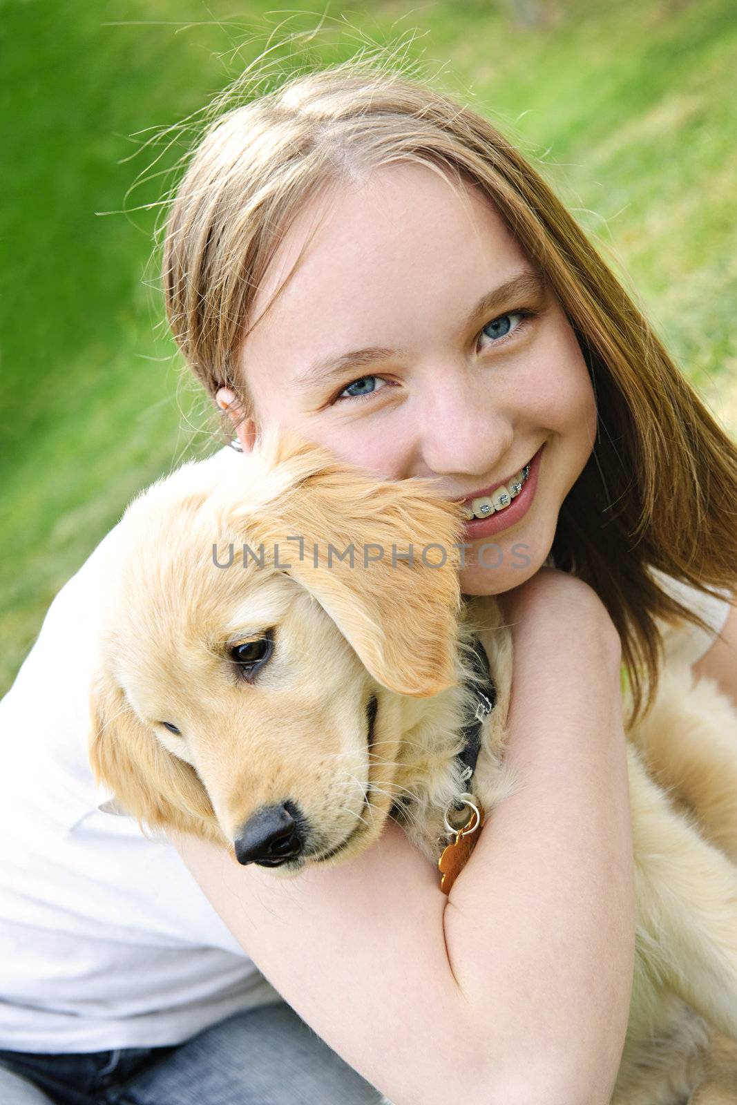 Portrait of smiling teenage girl holding golden retriever puppy