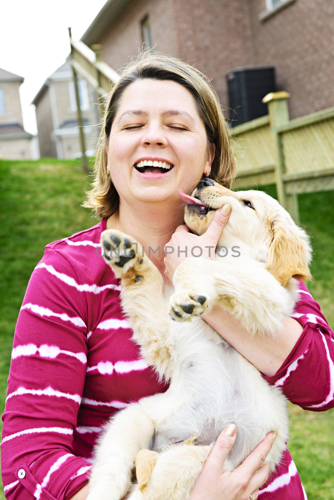 Portrait of laughing woman holding golden retriever puppy