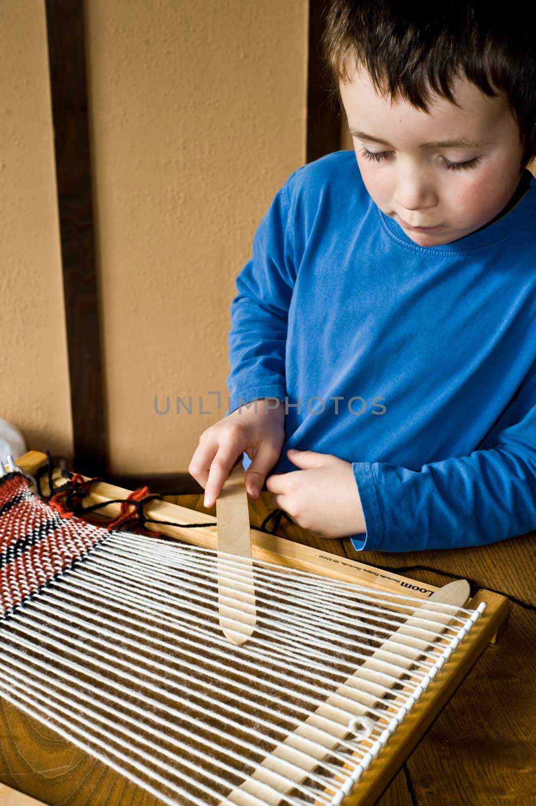 boy in blue preparing loom for weaving