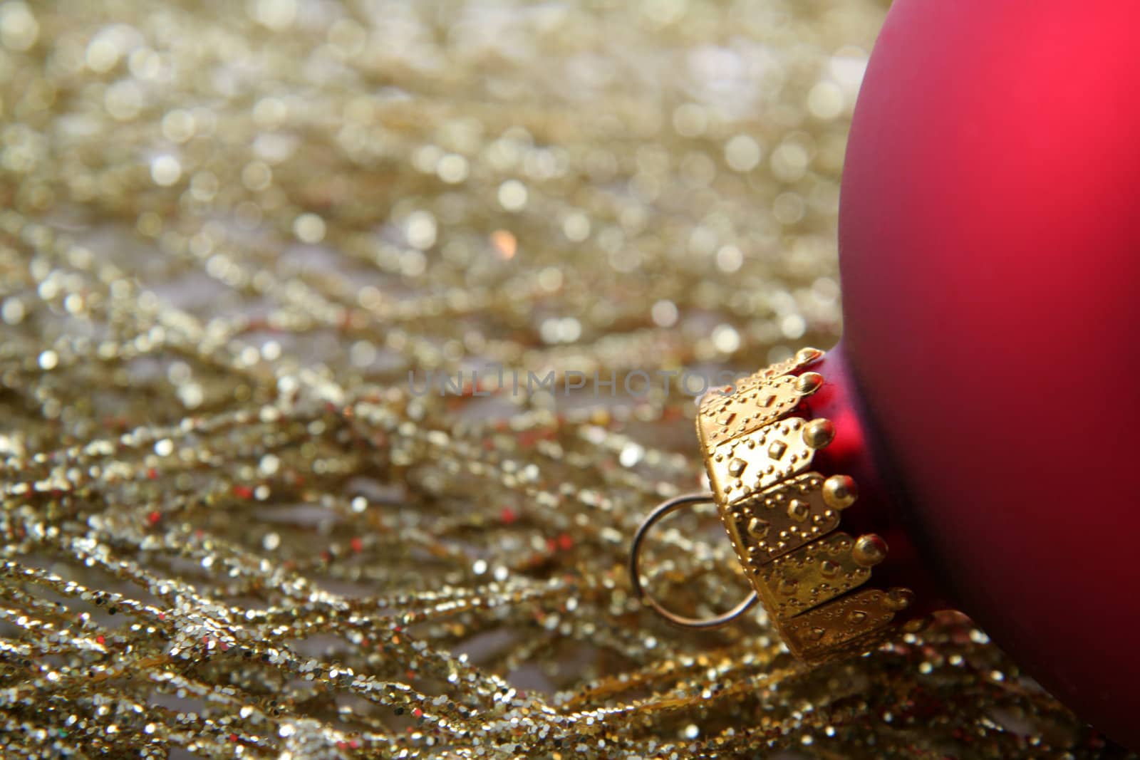 A red Christmas bauble sitting on gold decorative wrap.