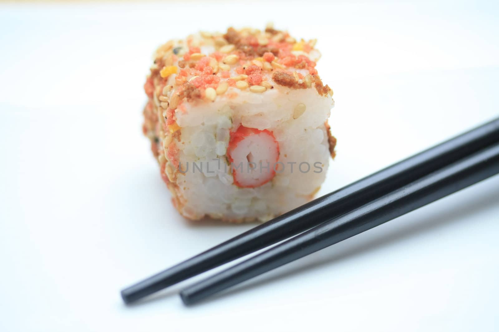 A piece of seame seed sushi and a pair of chopsticks