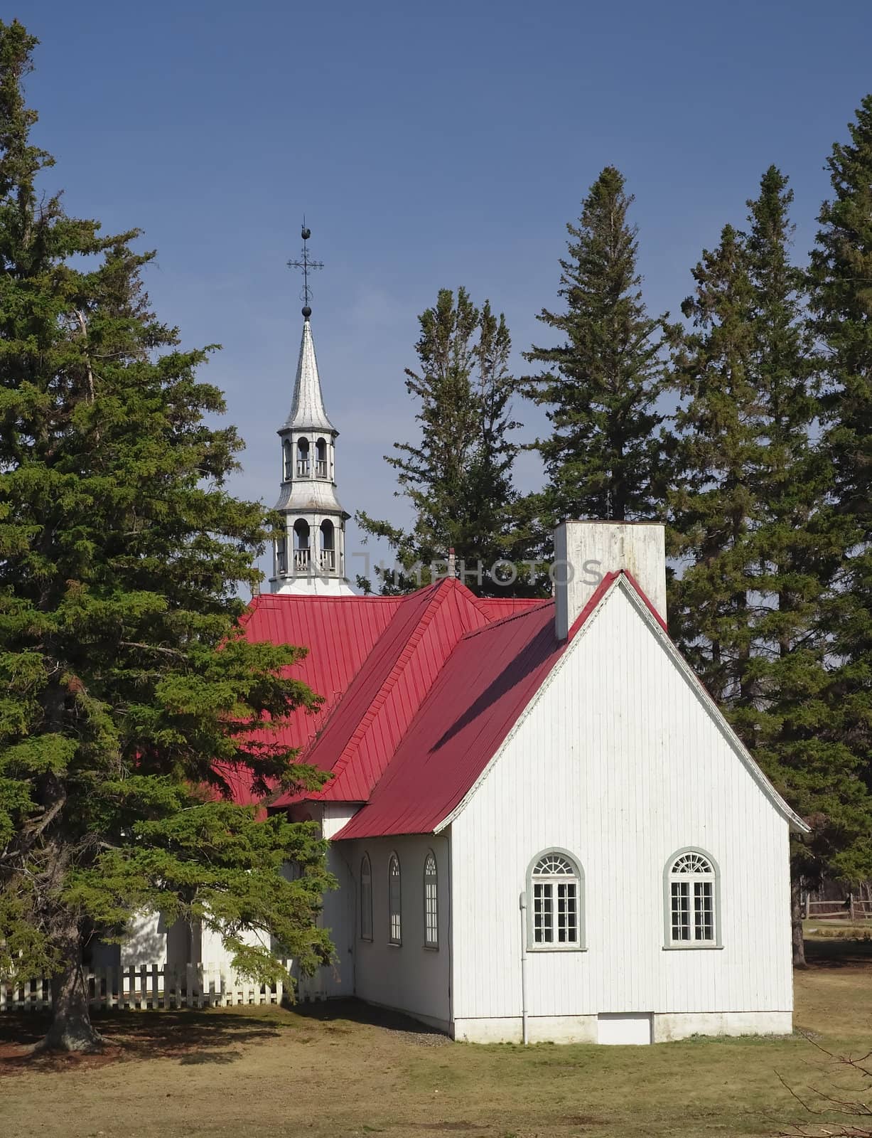 a small chapel with a red roof surrounded by trees