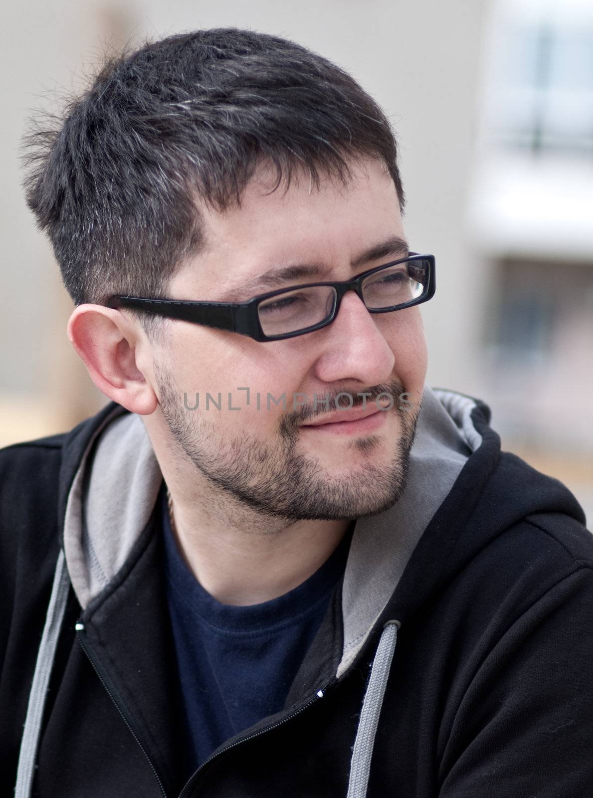 Portrait of a young male caucasian student with beard and glasses