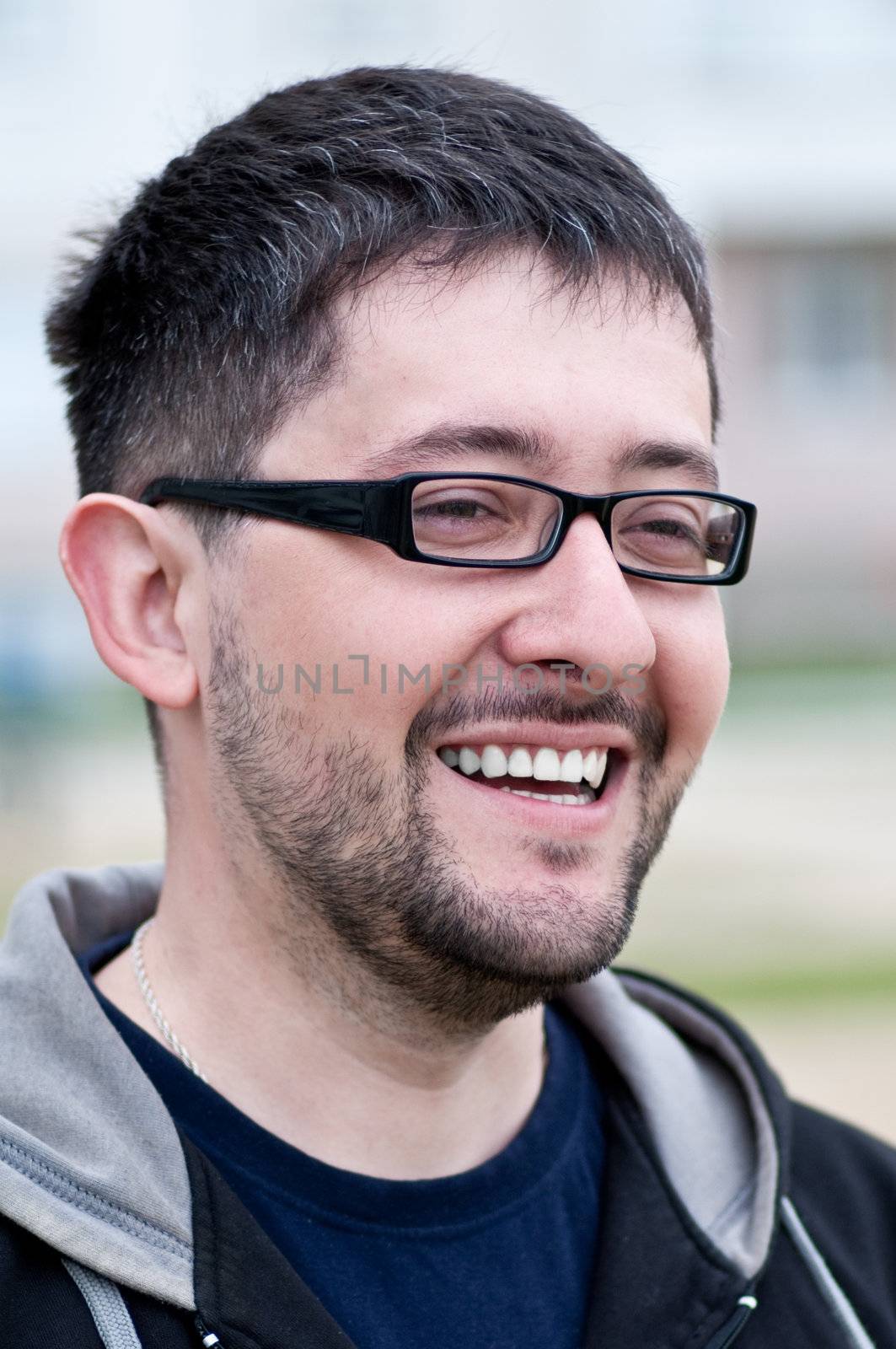 Portrait of a young smiling bearded man wearing glasses by Shpinat