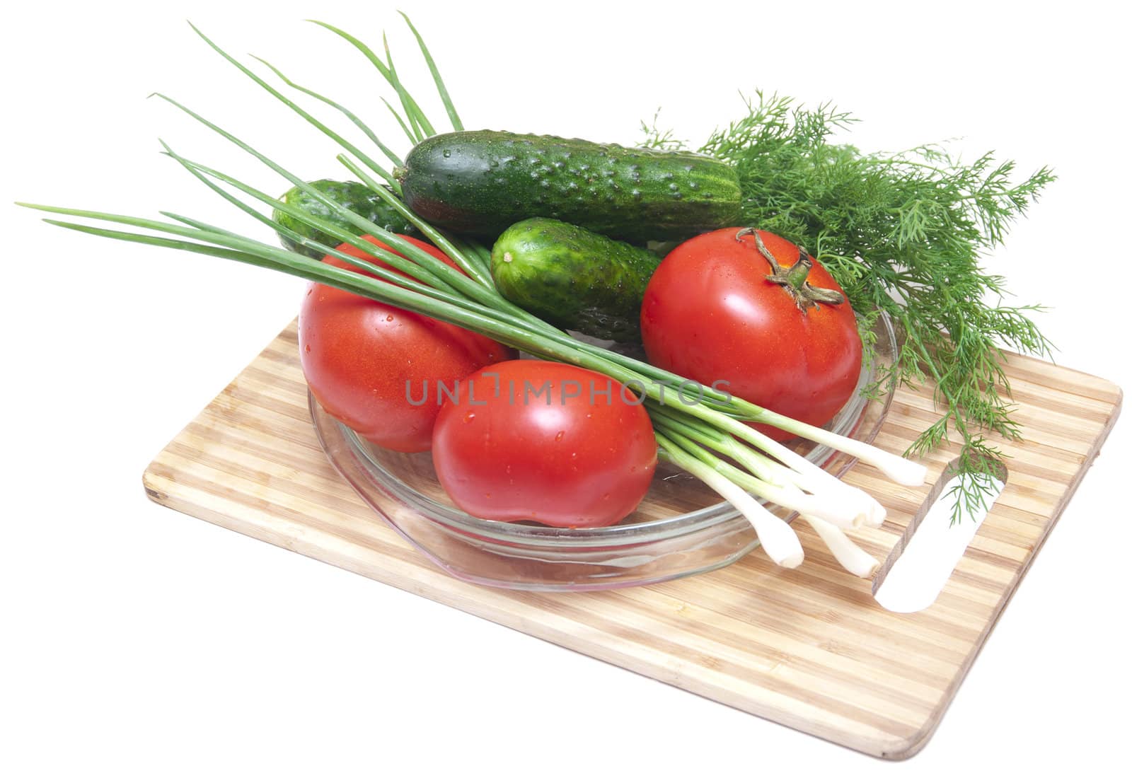 Cucumber, tomatoes and greens, close up on wooden board