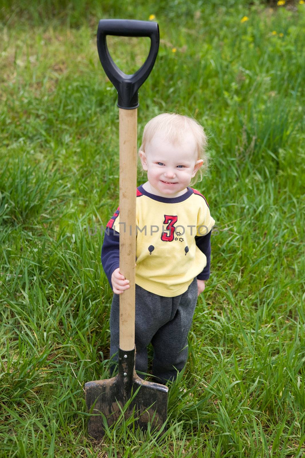 small girl with the shovel in the garden
