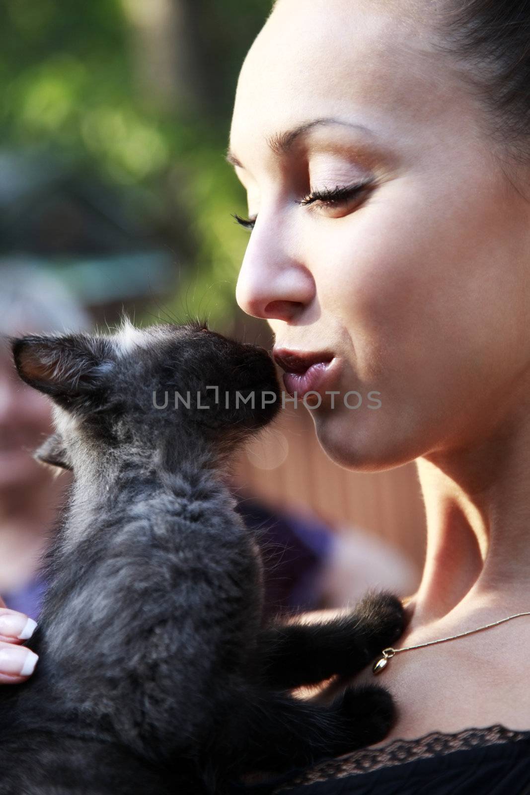 The young beautiful dark-haired woman holds in hands of a black kitten.