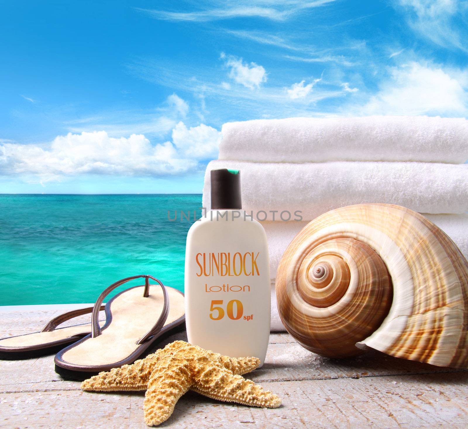 Sunblock lotion and white towels with ocean scene