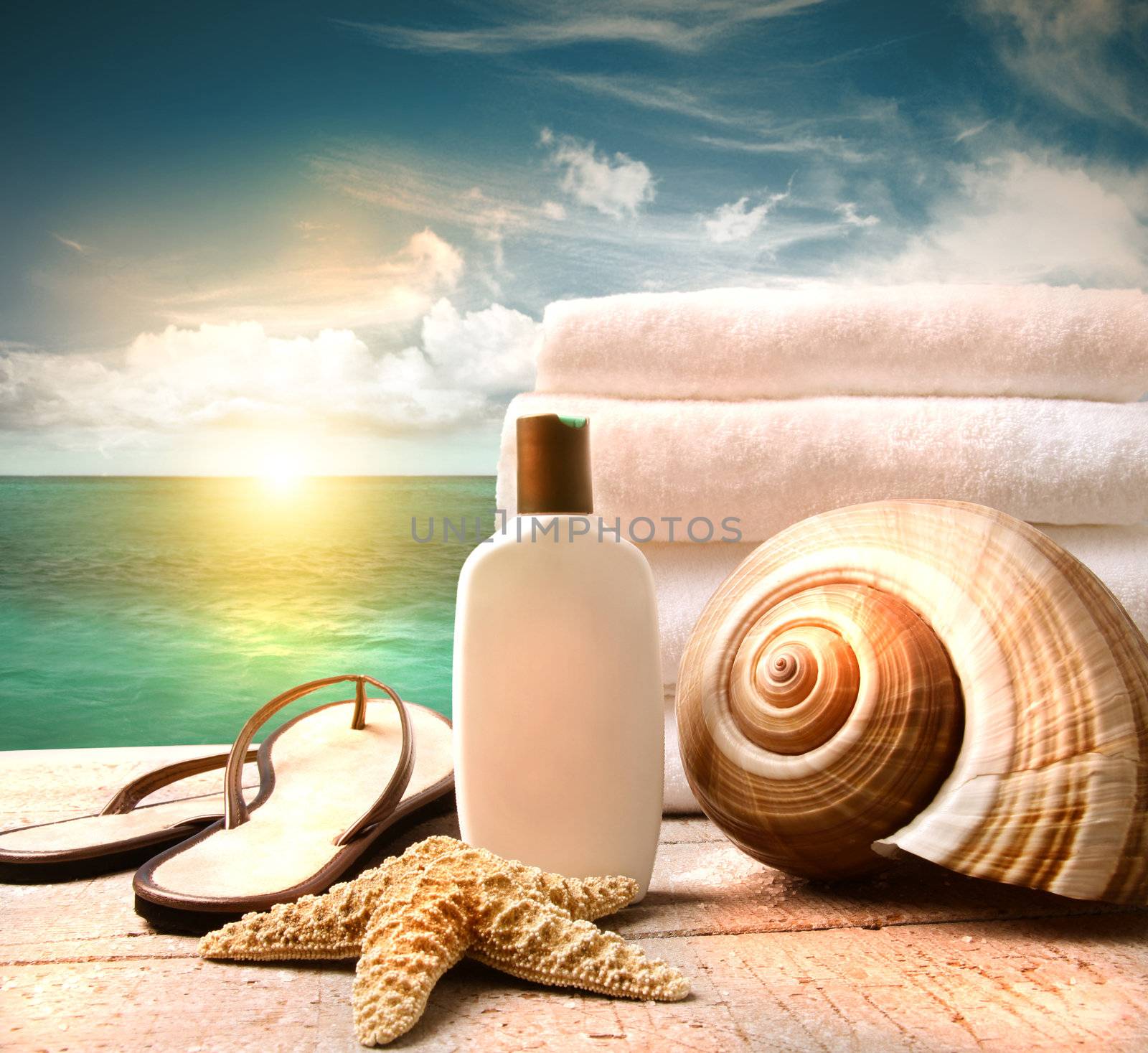 Sunblock lotion and white towels with ocean scene