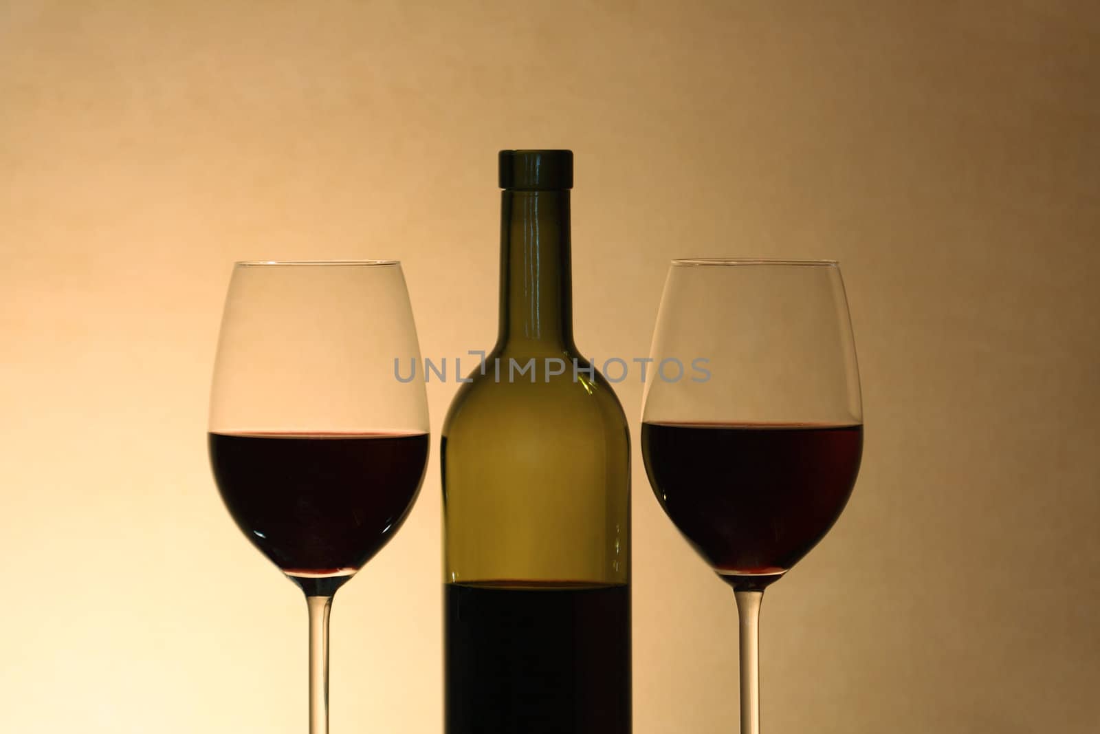Two wineglasses near bottle of red wine on gray background