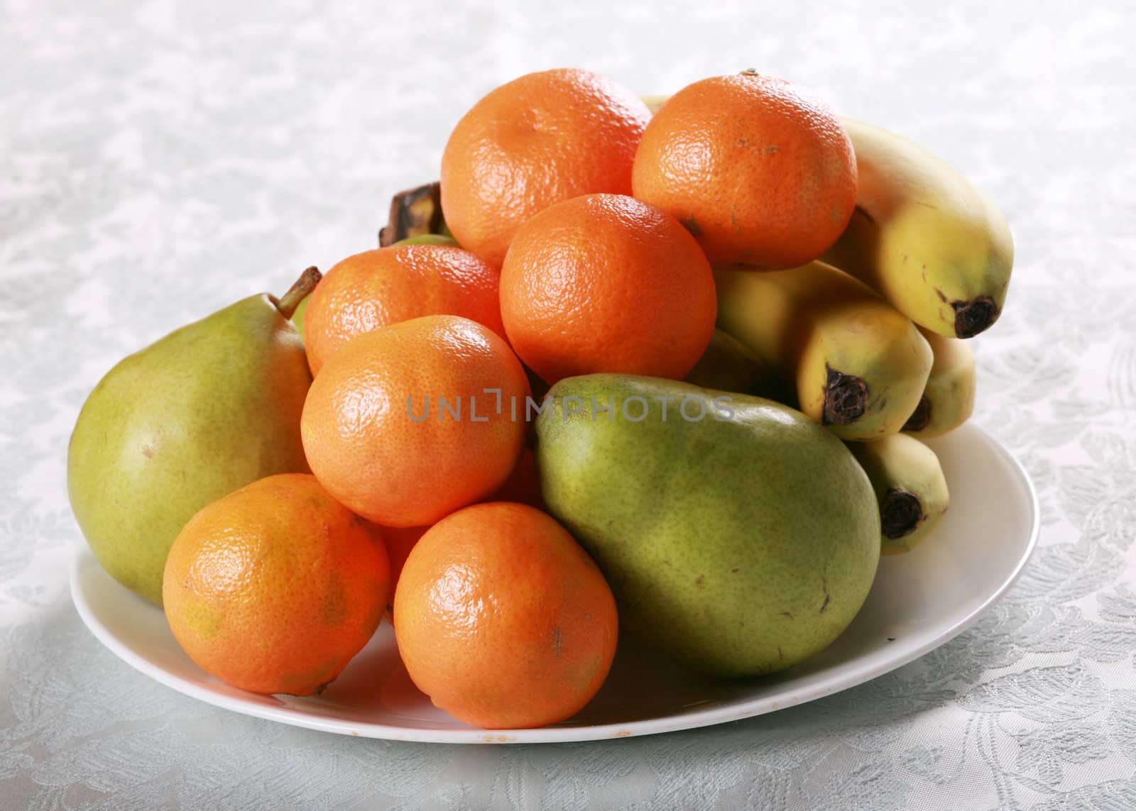 Plate of fresh fruit, clementine oranges, pears and bananas