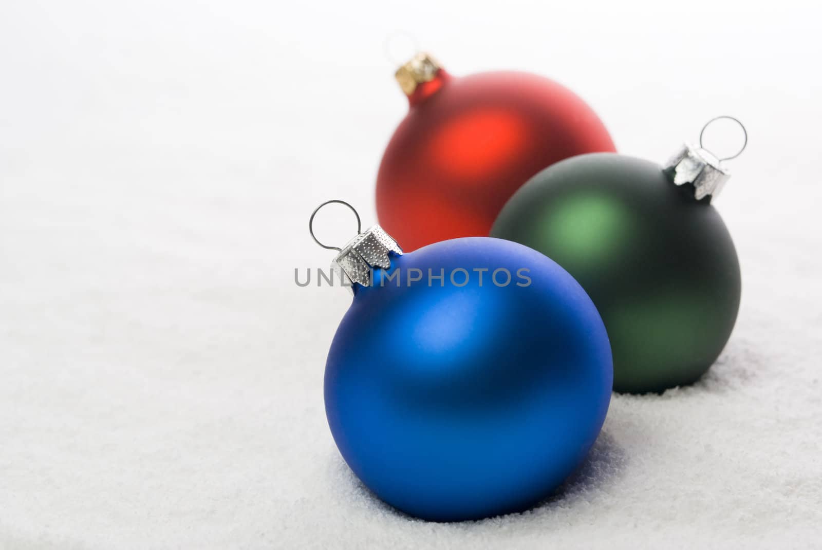 Red, Green and Blue christmas balls on the snow. aRGB.