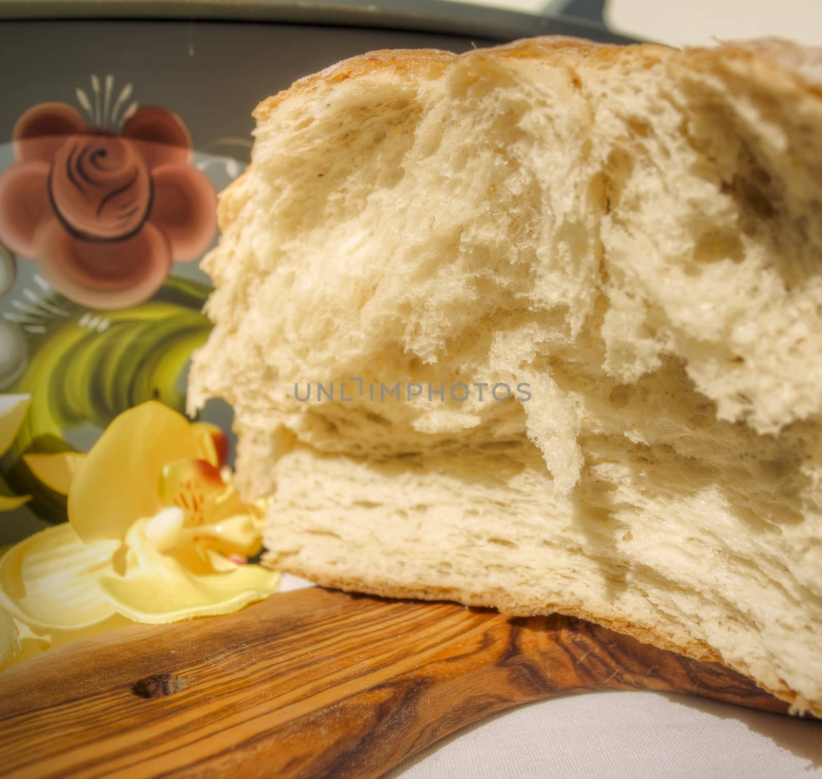 Fresh sliced bread with rose-painted bread basket in background.