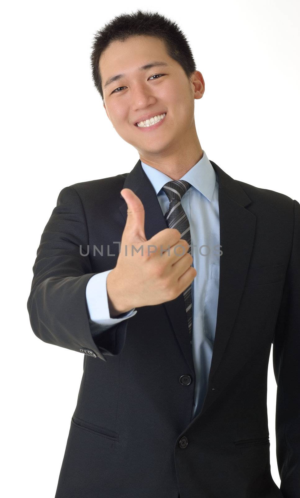 Smiling young business man of Asian giving you a thumbs up sign isolated against white.
