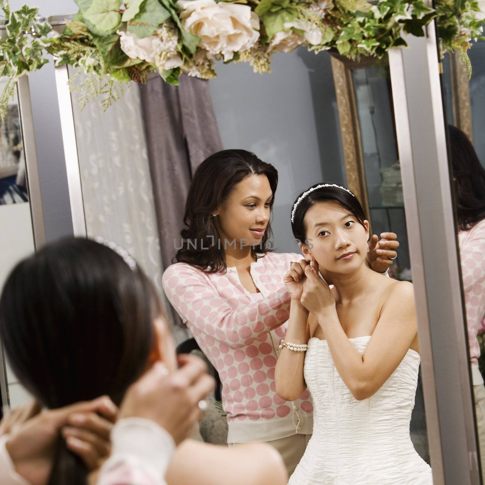 African-American woman helping Asian bride with hair.