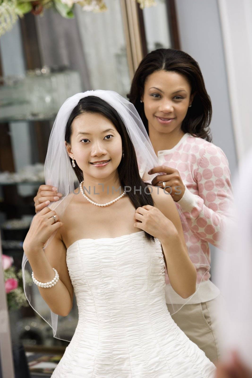 African-American friend holding Asian bride's veil.