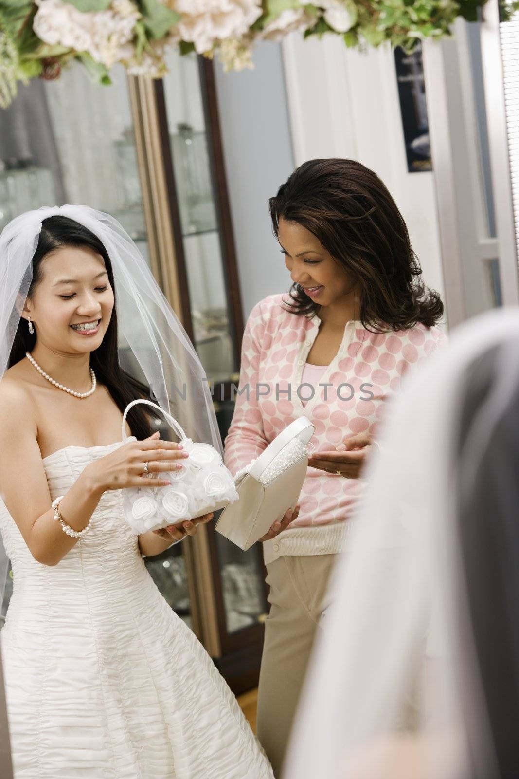 Woman helping bride with handbags. by iofoto