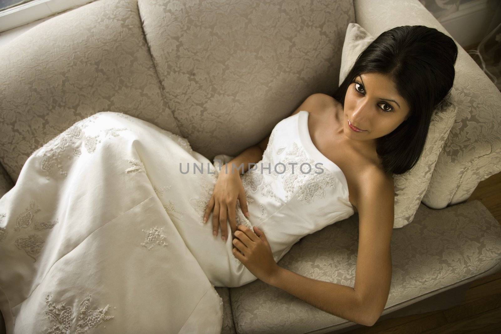 Portrait of an Indian bride lying on love seat.