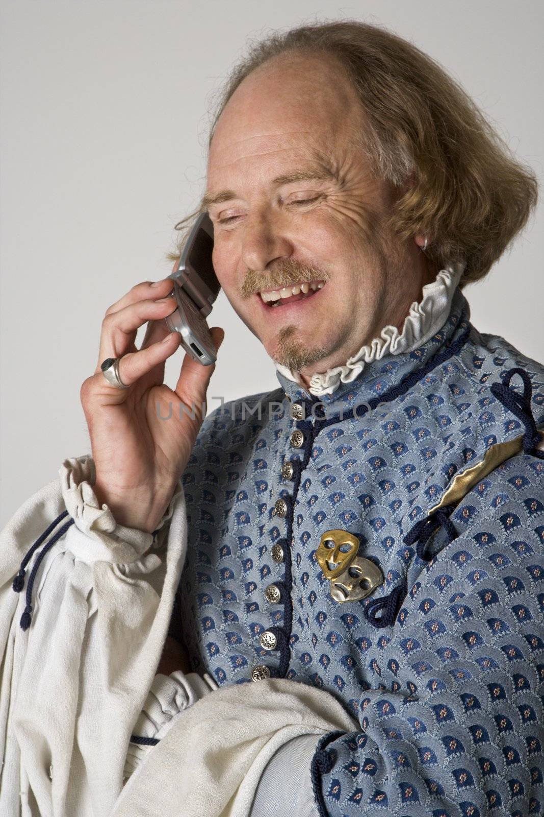 William Shakespeare in period clothing talking on cell phone and laughing.