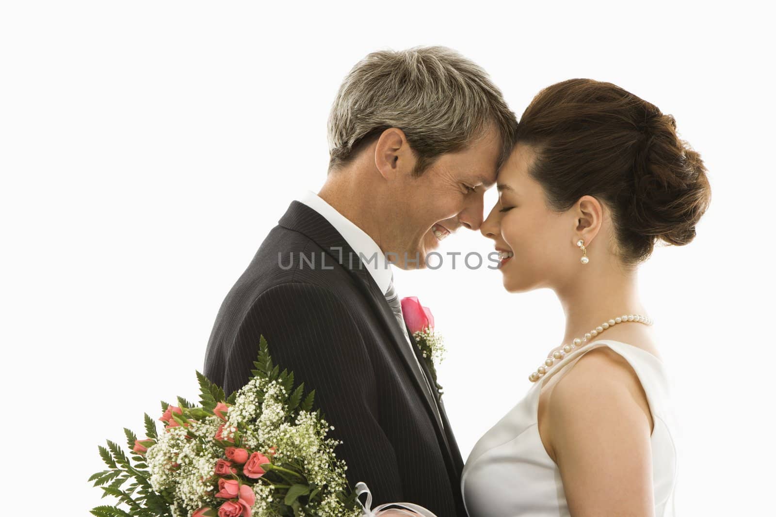 Portrait of Caucasian groom and Asian bride embracing