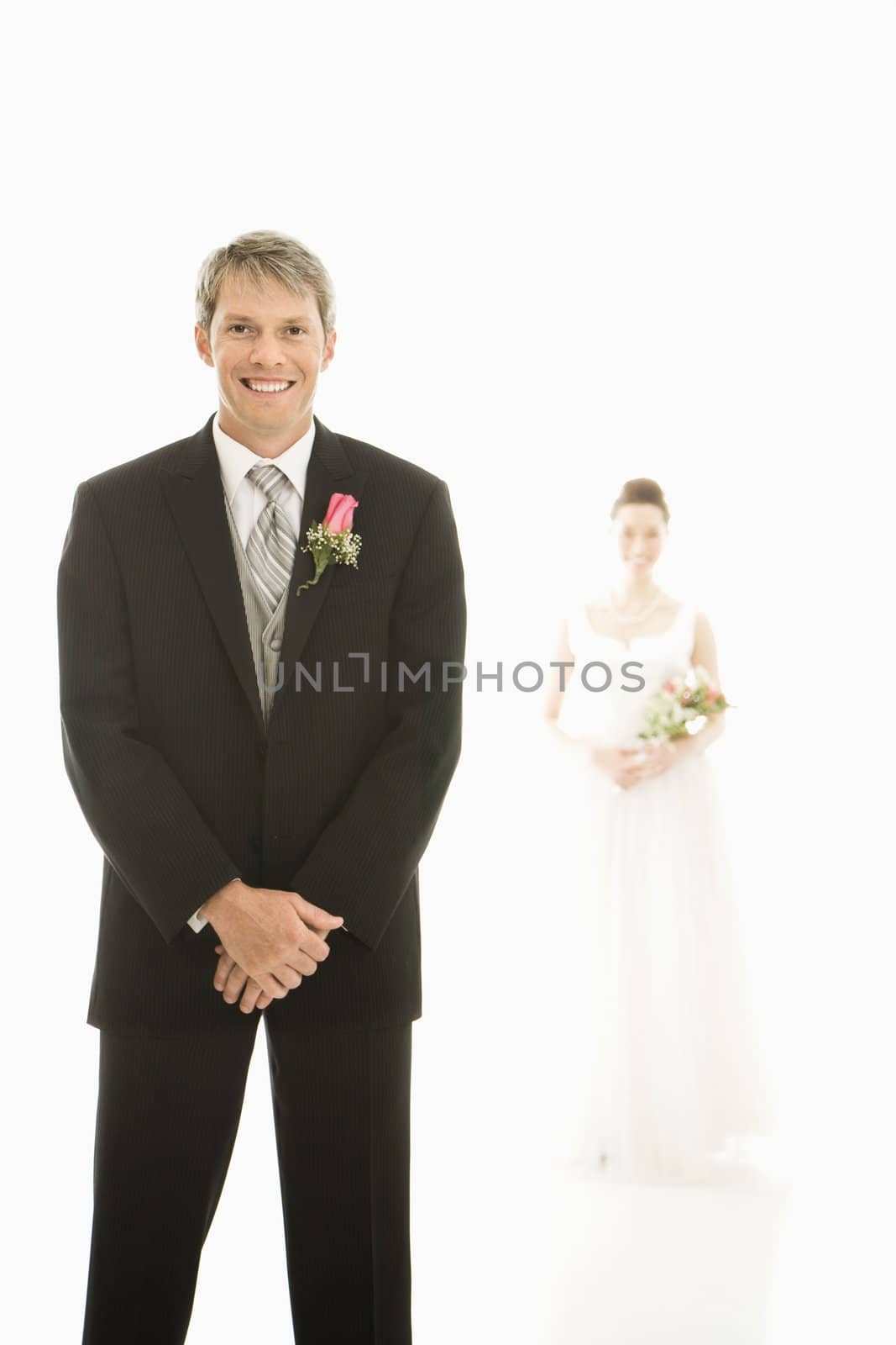 Caucasian groom in foreground and Asian bride in background.