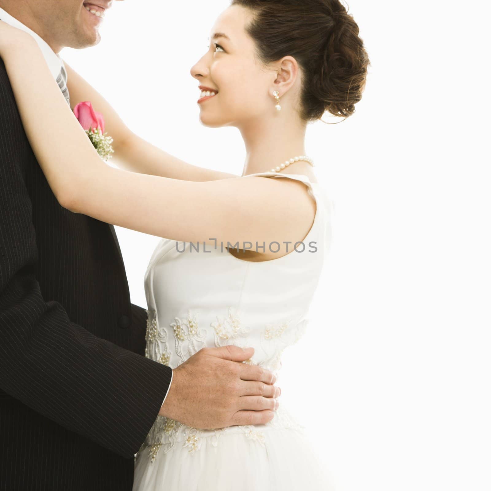 Caucasian groom and Asian bride dancing.