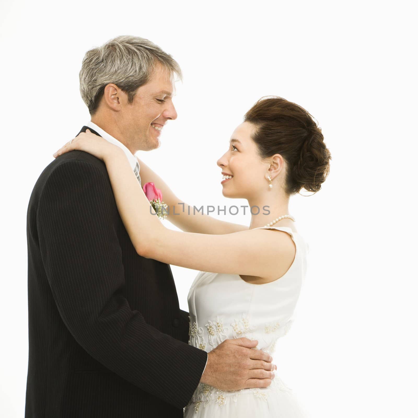 Caucasian groom and Asian bride dancing.