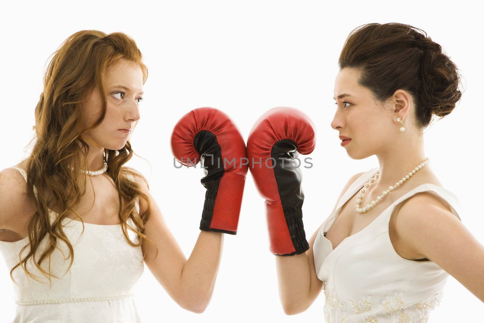 Caucasian bride and Asian bride holding boxing gloves up to each other.