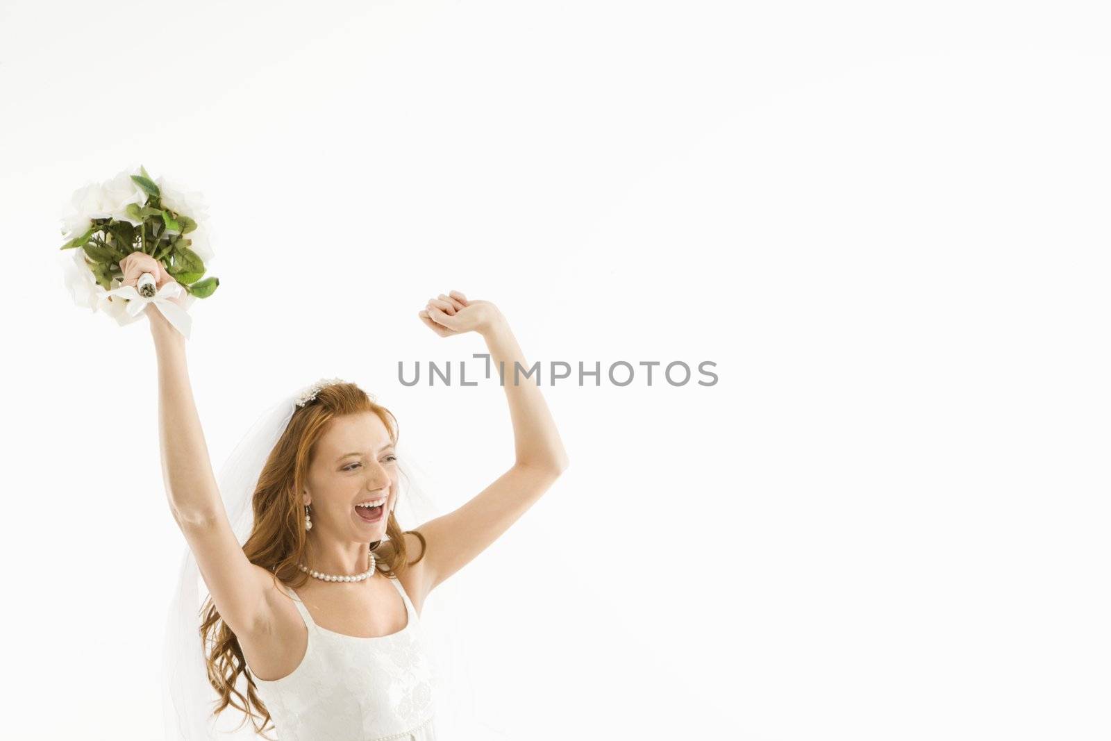 Portrait of Caucasian bride holding bouquet and raising arms.